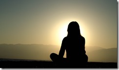 woman meditating at sunset